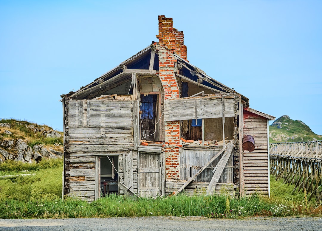 Dilapidated wooden house with exposed brick chimney, showing signs of decay and neglect, representing 'as-is' property condition for cash home buyers in Phoenix.