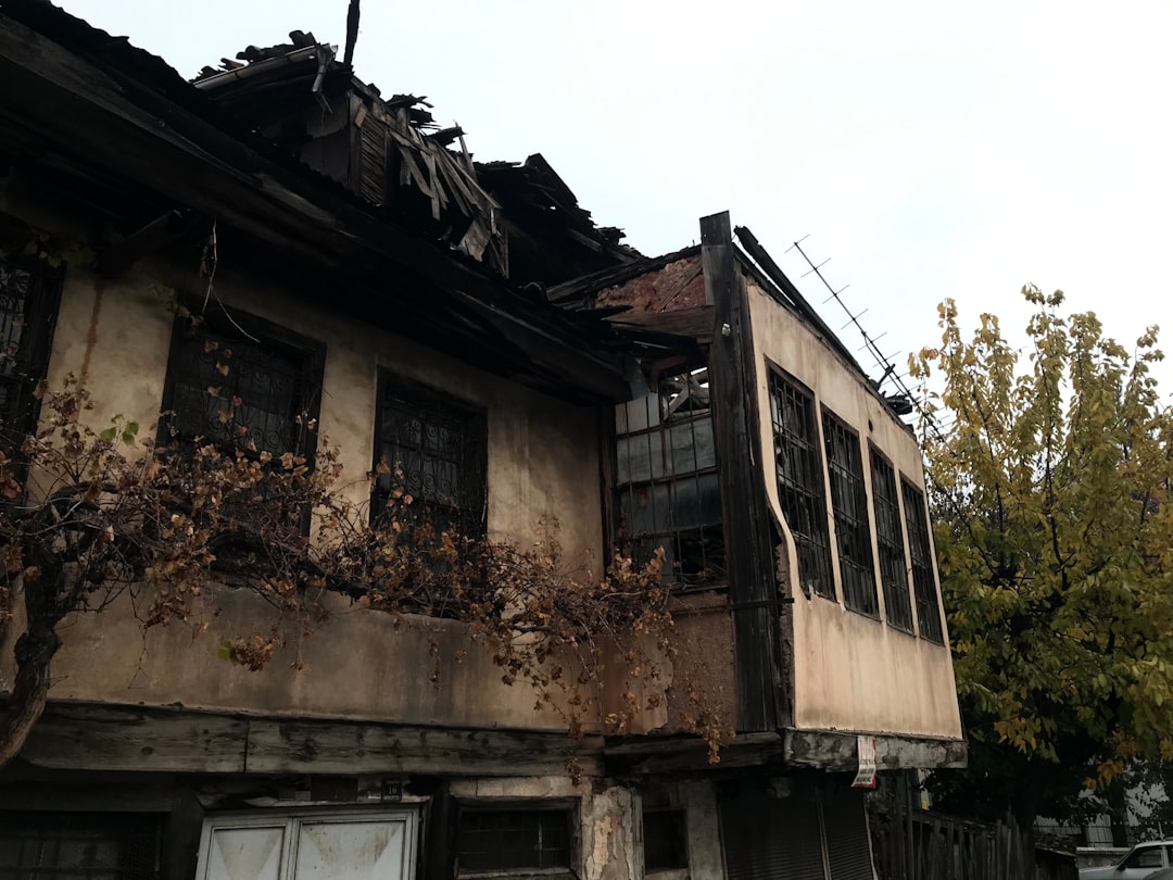 Fire-damaged house with a collapsed roof and broken windows, illustrating the challenges of selling a fire-affected property in Arizona.