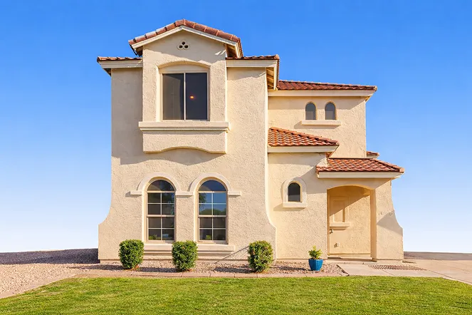 Two-story Scottsdale house with stucco exterior, tile roof, arched windows, and landscaped front yard. Ideal for cash buyers looking to sell homes quickly in Arizona.